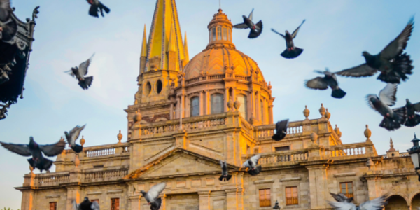 Church in Guadalajara, Mexico with pigeons flying overhead.