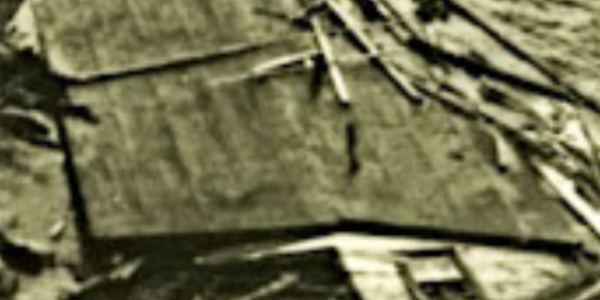 A collapsed house mostly sunken in ocean water.