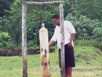 Man rings a large white tsunami bell outside.