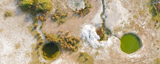 Desiccated landscape with two large holes in the land filled with green tinted water. Desiccated landscape with two large holes in the land filled with green tinted water.