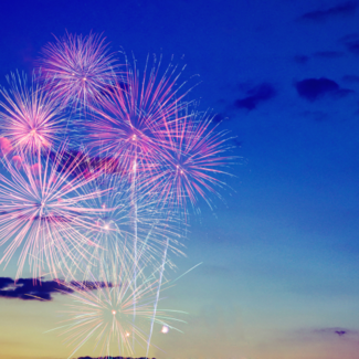 Fireworks bursting against a blue sky.