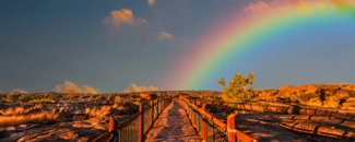 Bright half-rainbow looking out over a desert landscape with a boardwalk in the forefront. Bright half-rainbow looking out over a desert landscape with a boardwalk in the forefront.