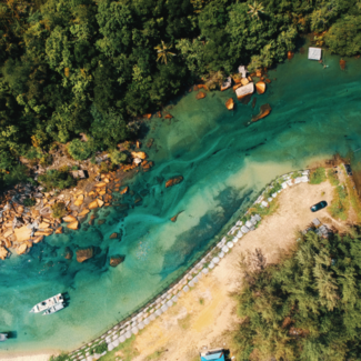 Aerial view of a river with a sandy bank on one side and a cluster of trees on the other side.