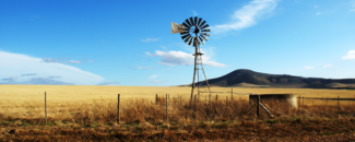 Windmill in a field with mountains in the background. Windmill in a field with mountains in the background.