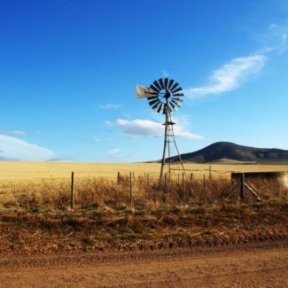 Windmill in a field with mountains in the background. 