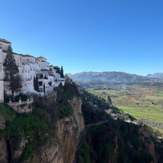 View of mountains and fields and part of the town of Ronda, Spain.