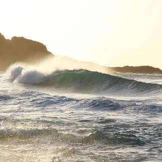 Waves crashing on beach cliffs during sunrise. 