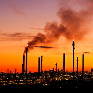 Alt Text: Smoke stacks in Spain against a red and yellow-hued sunset.