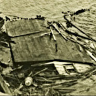 A collapsed house mostly sunken in ocean water.