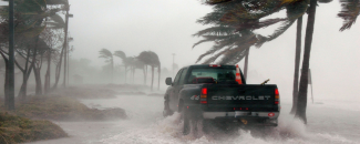 Alt Text: Black Chevrolet truck driving through flood waters and windy conditions. Alt Text: Black Chevrolet truck driving through flood waters and windy conditions.