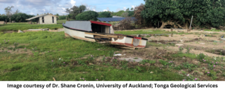 A damaged boat washed up into the middle of a field in front of a hut. A damaged boat washed up into the middle of a field in front of a hut.