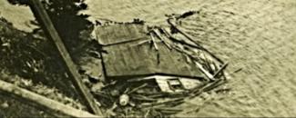 A collapsed house mostly sunken in ocean water.