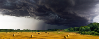 Assessing the U.S. Climate in May 2024 Alt Text: Storm clouds gathering above a field covered in hay bales.