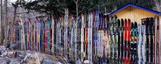 Photo of skis lined up vertically near a shed Photo of skis lined up vertically near a shed